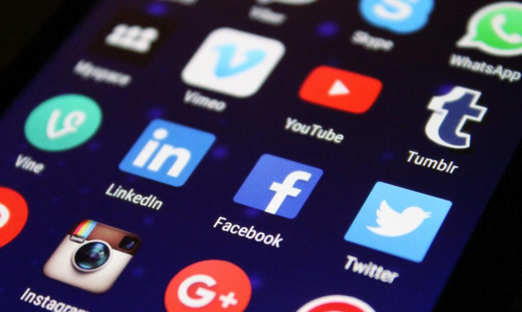 Close-up of a smartphone screen showing various social media app icons such as Facebook and Twitter.
